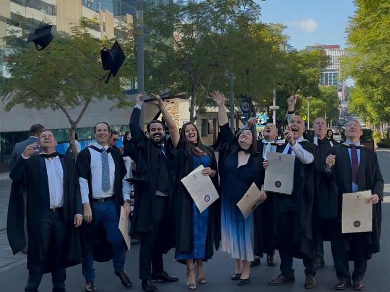 UniSA graduates throwing their mortarboards into the air 