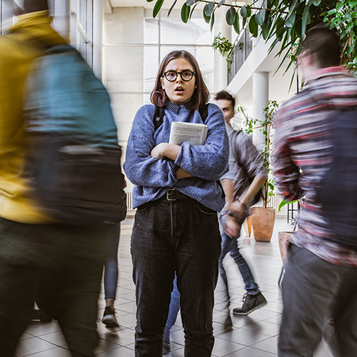 Anxious teenager in hallway filled with students