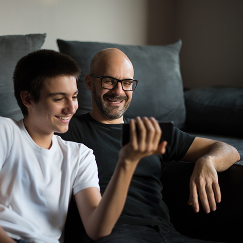 Son with his Dad watching something on the phone