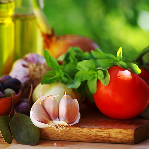 Display of colourful vegetables and jug of olive oil