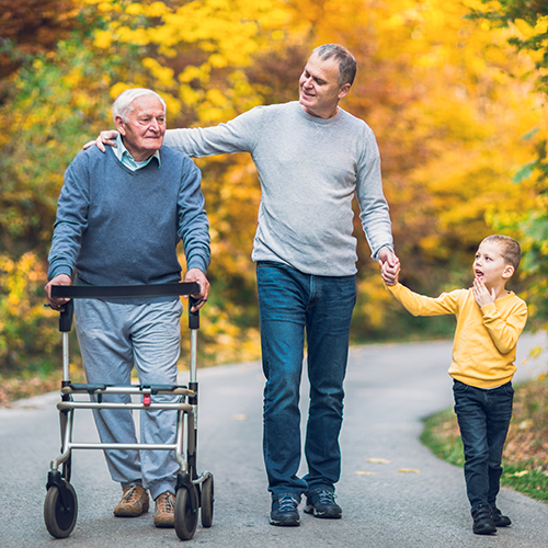Older man walking with his son and grandson in an autumn park