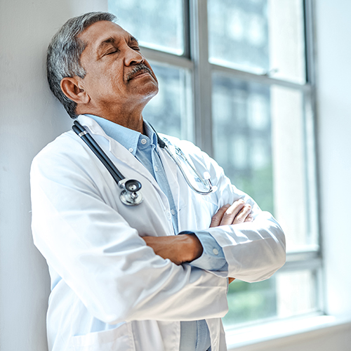 Tired doctor leaning against a wall