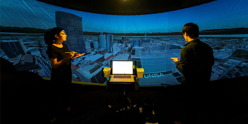 Two UniSA PhD students using UniSA&rsquo;s Hyve-3D facility, which removes the need to wear VR goggles, enabling everyone in the room to immerse in a virtual environment and directly interact through 3D sketching.