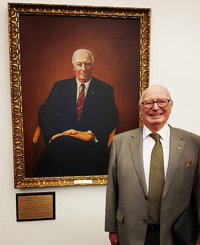Sir Eric Neal next to his portrait, which is displayed in the Sir Eric Neal Library at UniSA&rsquo;s Mawson Lakes campus.