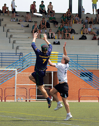 Daniel Roberts reaching high in the #7 shirt playing ultimate frisbee 
